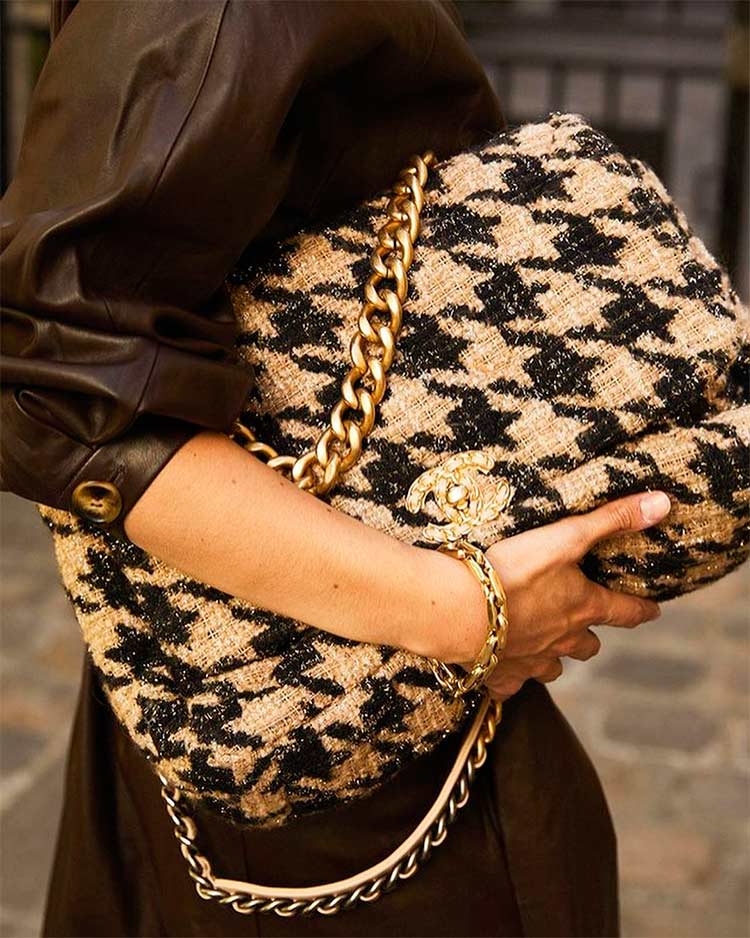 La mano de una mujer sujeta un bolso de estilo retro de Chanel. 