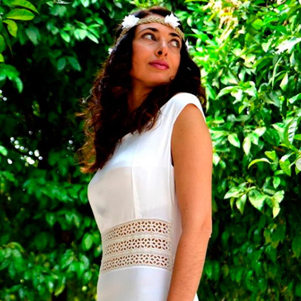 Chica morena posando con un vestido veraniego blanco de la marca Marina López Moda Sostenible.
