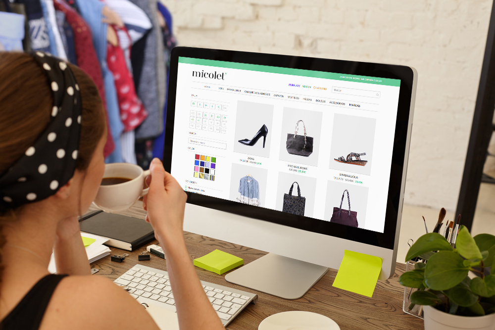  Mujer de pelo castaño con un pañuelo negro con topos blancos evita comprar fast fashion comprando ropa de segunda mano desde su ordenador en la web de Micolet.
