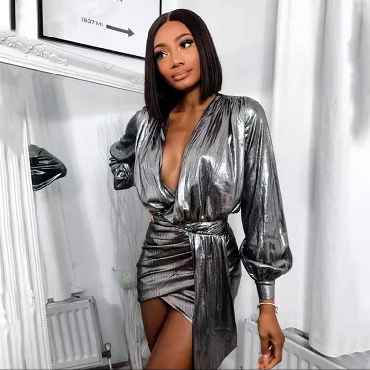 Una joven posa con un look de fiesta, un vestido mini metalizado en color plata con una lazada en la cintura, la prenda necesaria para tu fondo de armario 2020. 