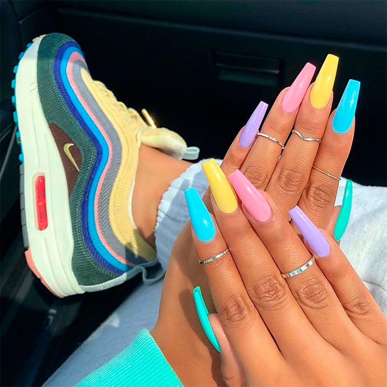 Aparecen las manos de una mujer con las uñas pintadas en los mismos colores que las zapatillas que tiene puestas, las zapatillas tendencia colores Nike. 
