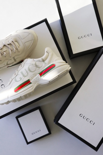 Zapatillas de color blanco, rojo y verde de la marca Gucci acompañado de su caja de color blanco y negro, compradas en una tienda de ropa barata u outlet.