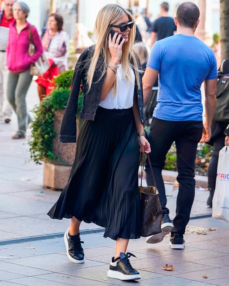 La modelo Heidi Klum camina por la calle con un look zapatillas negras, una clara tendencia 2020 zapatillas a tener en cuenta si quieres comprar zapatillas negras mujer, con un outfit casual con falda midi y chaqueta denim negra. 