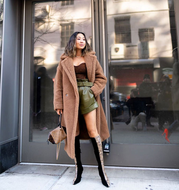 La influencer Aimee Song posa con un look New York Fashion Week de Mr Self-Portrait, con un short y top con un abrigo largo de borrego y unas botas altas. 