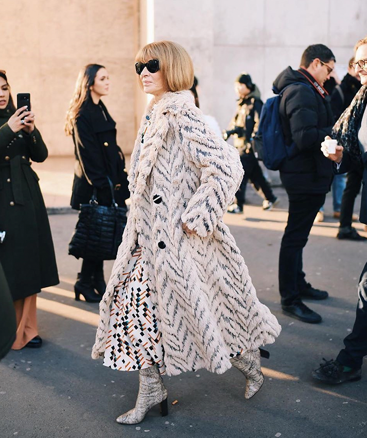 Anna Wintour es fotografiada por la calle con un look en tonos claros, unas botas y un abrigo de piel, es la mujer más poderosa de la moda.