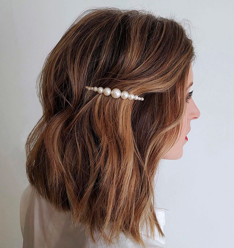 Una chica joven lleva un peinado desenfadado con una horquilla tendencia de perlas que hace su look más bonito y cool, uno de los complementos de moda