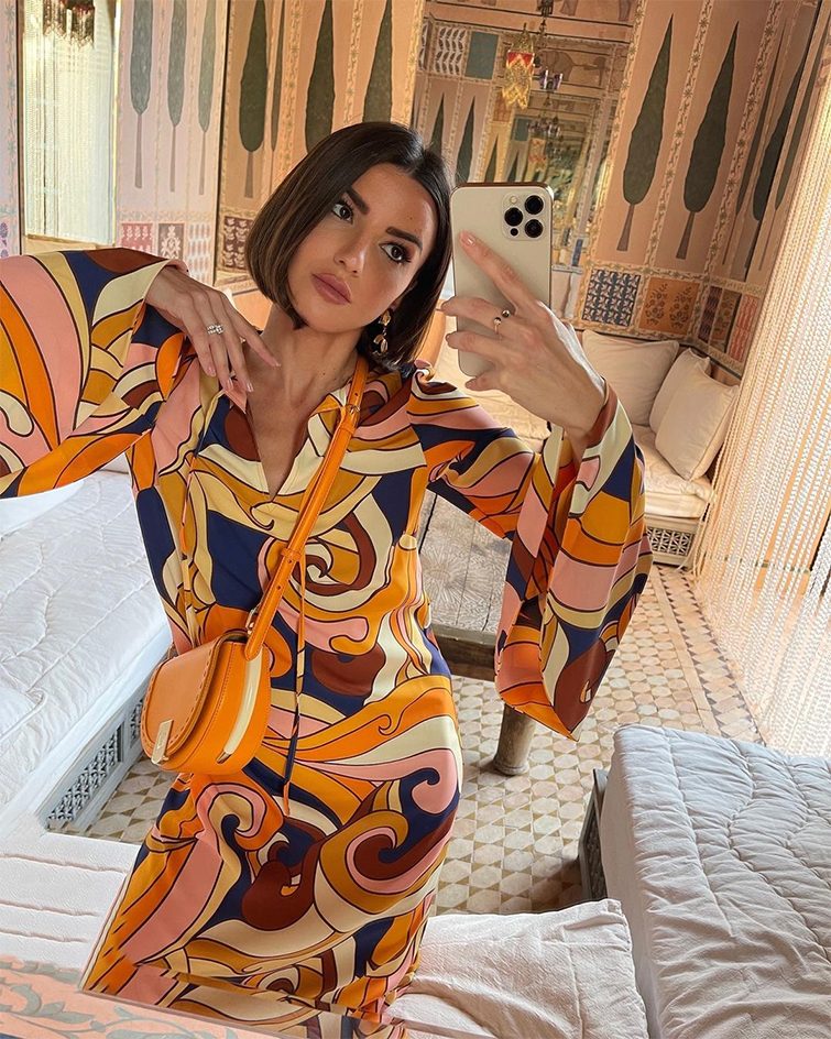 Alexandra Pereira, una de las top 10 influencers de moda en Espala, posa con un vestido y bolso en tonos naranjas para hacerse un selfy,