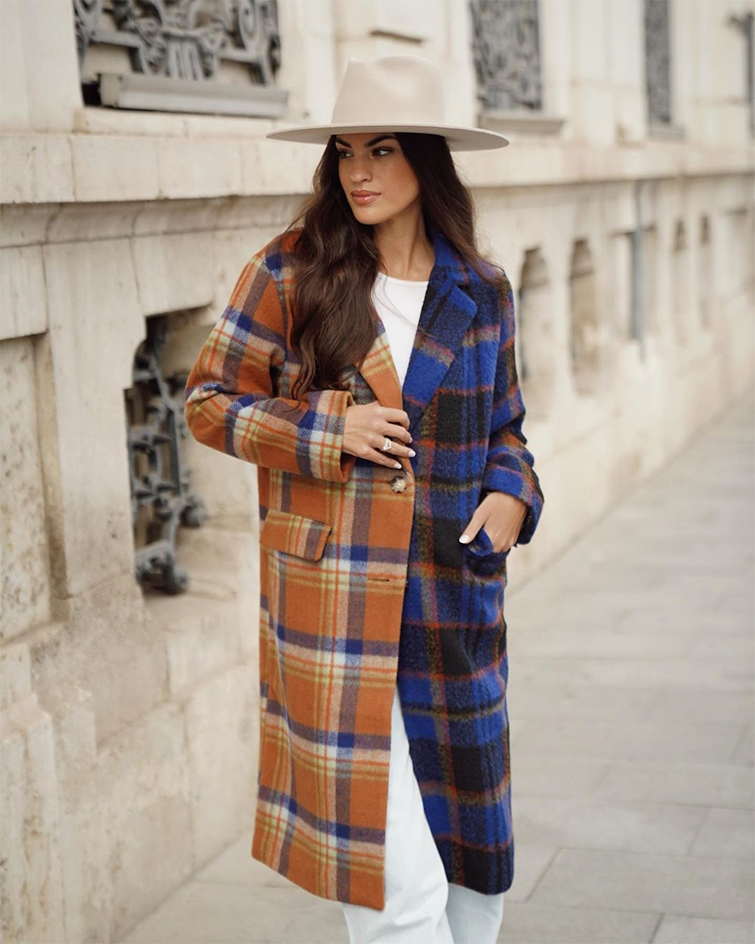 Marta Lozano es una de las top influencers de moda de España. En la foto la podemos ver en una calle, tapada con un abrigo de cuadros de colores azules y marrones, pantalón blanco y sombrero claro