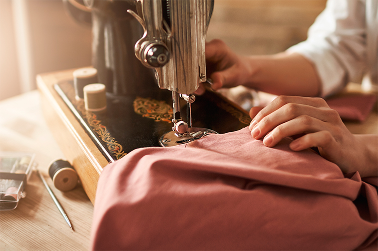 Maquina de coser con la que una mujer está arreglando una prenda de ropa con el objetivo de conseguir una armario con ropa sostenible barata