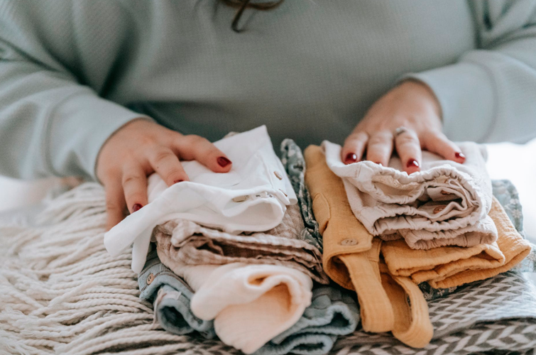 Una mujer apila ropa de bebé, es una de las cosas de segunda mano muy baratas