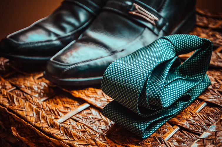 Ropa segunda mano hombre vintage de estilo formal, zapatos de vestir y corbata sobre una mesa