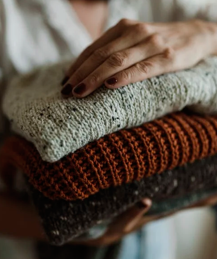 Mujer sostiene en sus brazo prendas dobladas que pueden comprarse todo a 2 euros online